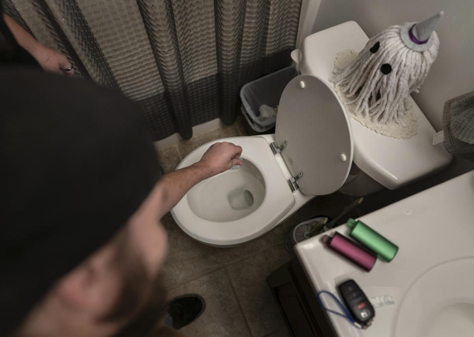 Tyler Baker flushes fentanyl as his peer support worker Jesse Johnson of the Family Resource Center stands at left, in Findlay, Ohio, Thursday, Oct. 12, 2023. After talking with Johnson, Baker, an active user, agreed to dispose of his supply of fentanyl. The powerful lab-produced opioid has driven the number of fatal drug overdoses in the U.S. to record levels. (AP Photo/Carolyn Kaster)