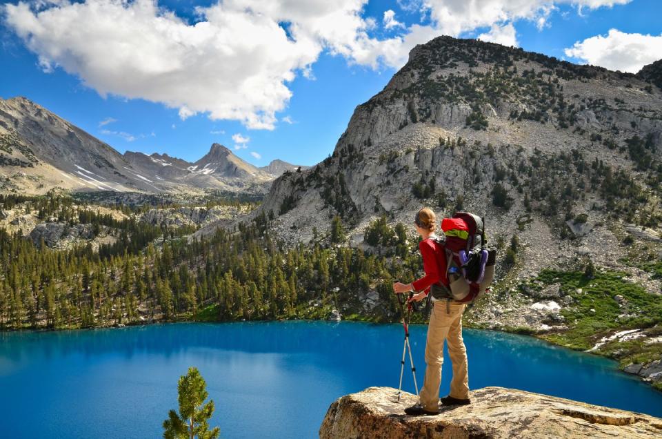 a woman looks out over the aqua blue colored marion lake in kings canyon national park, california