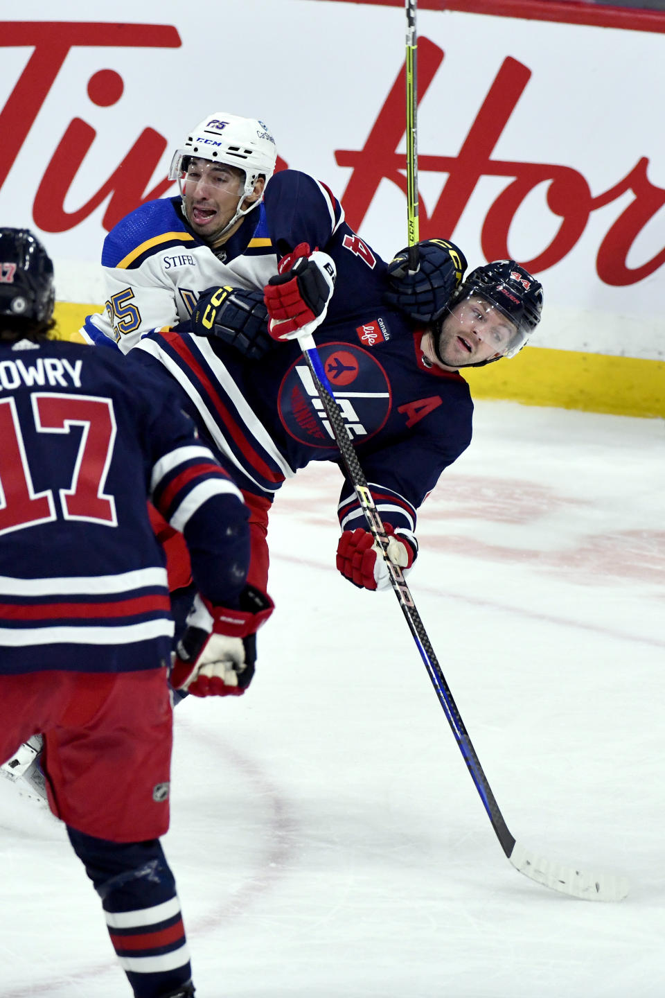 St. Louis Blues' Jordan Kyrou (25) checks Winnipeg Jets' Josh Morrissey (44) during the third period of an NHL hockey game Tuesday, Oct. 24. 2023, in Winnipeg, Manitoba. (Fred Greenslade/The Canadian Press via AP)