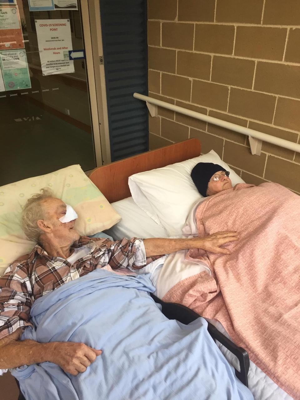 Danny Rowland reaches out to his wife Shirley as they lay next to each other in a hospital bed. 