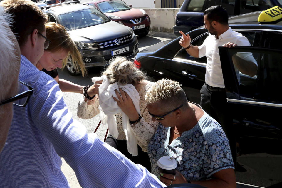 A 19-year old British woman, center, covers her face as she arrives at the Famagusta court for the first day of her trial, in Paralimni, Cyprus, Wednesday, Oct. 2, 2019. The 19 year old British woman pleaded not guilty to making up an accusation that she was raped by a dozen Israelis at a hotel in a Cypriot resort town. (AP Photo/Petros Karadjias)