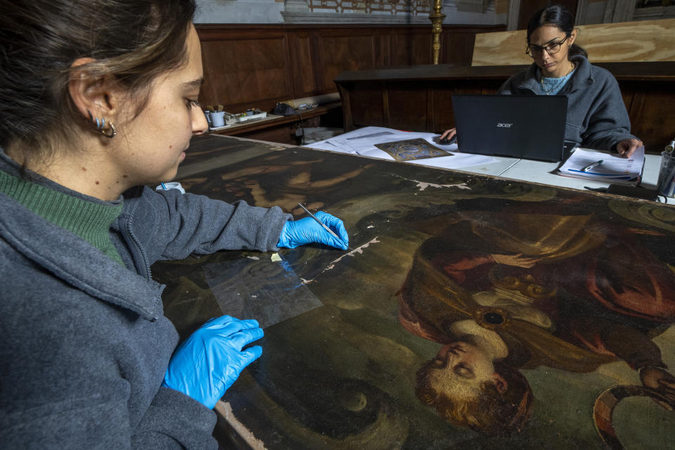 Restorers Annalisa Tosatto, right, and Alice Chiodelli work at the conservation and study of ' The reward and a pair of putti', a 1590 painting by Venetian Renaissance artist Andrea Michieli known as Andrea Vicentino in a makeshift laboratory set up in the Venetian Doge's private chapel inside Palazzo Ducale in Venice, northern Italy, Wednesday, Dec. 7, 2022. The 93x330 centimeters (approximately 36.6x130 inches) canvas was adorning the Grimani's Hall in the Doge's apartments of Palazzo Ducale. (AP Photo/Domenico Stinellis)