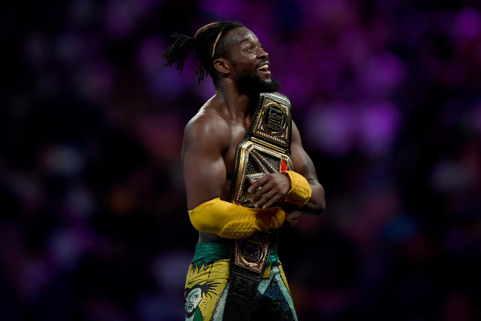 WWE Superstar Kofi Kingston celebrates and holds the championship belt.