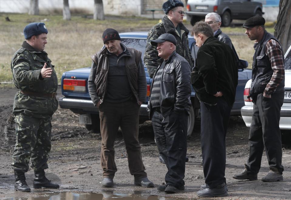 A Ukrainian officer talks with a pro Russian activist in their camp near the armory Ukrainian army where they stand to prevent the export of arms and ammunition in the village of Poraskoveyevka, eastern Ukraine, Thursday, March 20, 2014. The disheveled men barricading the muddy lane leading into a military base in this eastern Ukraine village say they're taking a stand to defend Russian-speakers. (AP Photo/Sergei Grits)