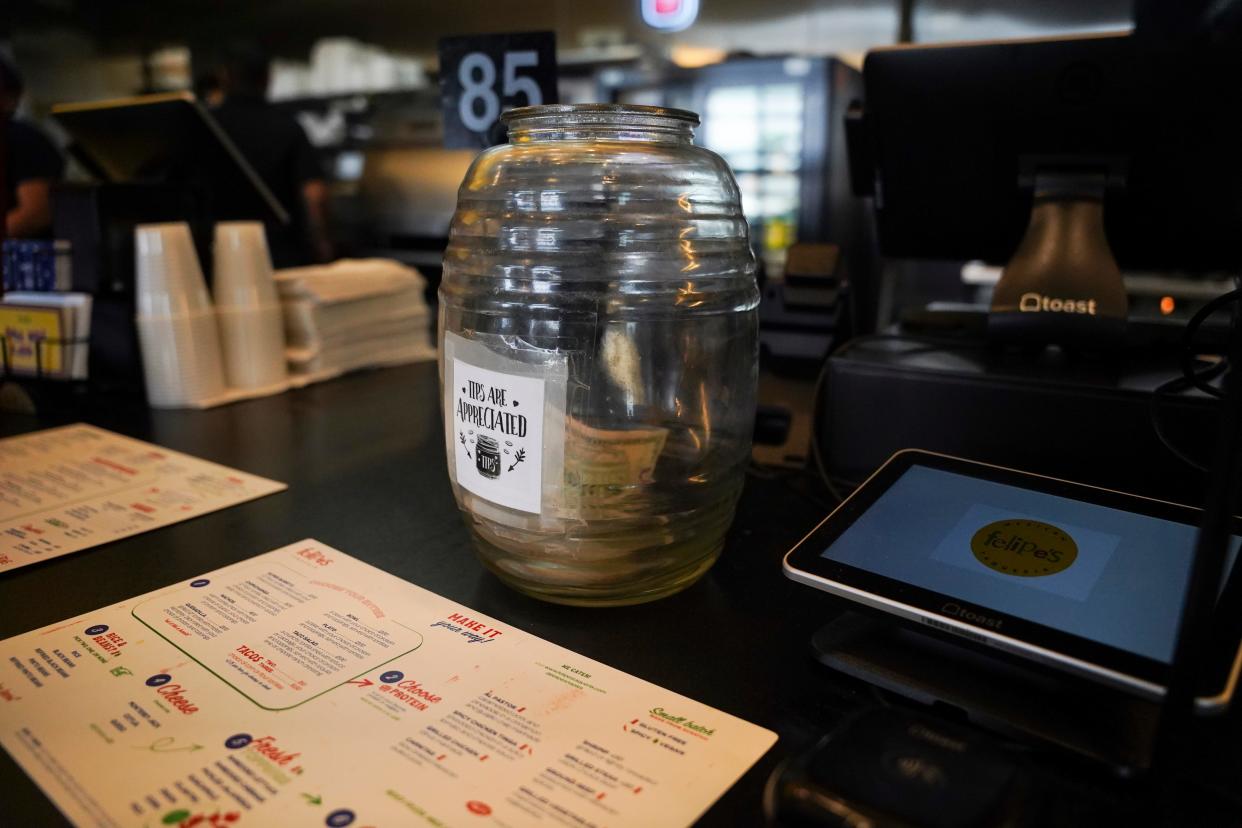 A tip jar stands on the counter in a Naples restaurant.