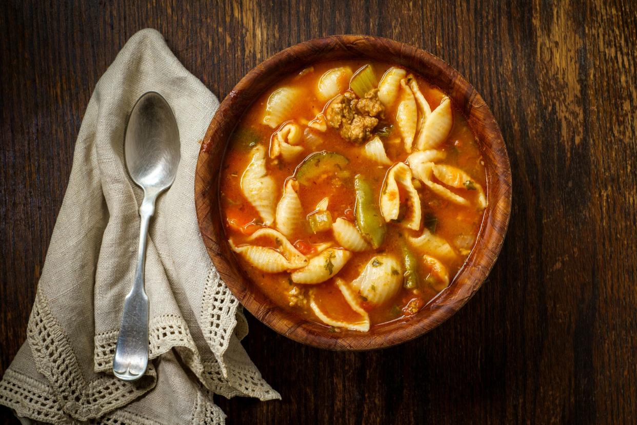 Hearty Italian minestrone soup with sausage in wooden bowl