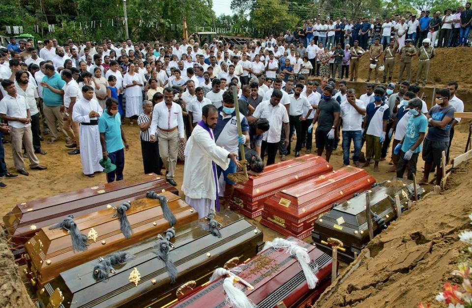 A priest conducts religious rituals during a mass burial for Easter Sunday bomb blast victims in Negombo, Sri Lanka (PA)