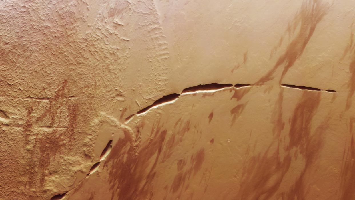  A satellite photo of mars with a massive, curved crack in its surface. 