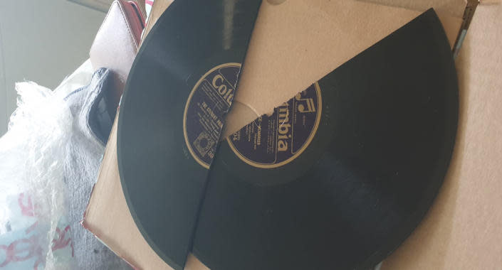 A vinyl record snapped in half on top of a cardboard box. 