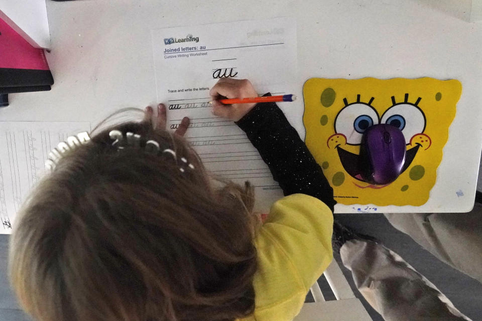 Anabelle Chao works on a cursive writing exercise after having finished remote learning for the day, Thursday, Oct. 1, 2020, at her home in North Miami Beach, Fla. Rather than wait to see how the Miami-Dade school system would handle instruction this fall, Erica Chao enrolled her two daughters in a private school that seemed better positioned to provide remote learning than their public elementary school was when the coronavirus first reached Florida. (AP Photo/Wilfredo Lee)