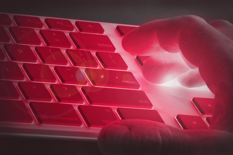 Red-lit image of a hand on a keyboard