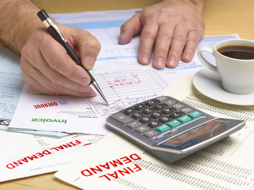 Person reviewing finances with calculator and paperwork on desk