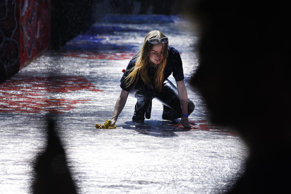 A worker attempts to dry the runway during a steady rain before the Tommy Hilfiger Fall 2022 collection show during Fashion Week, Sunday, Sept. 11, 2022, in New York. (AP Photo/Jason DeCrow)