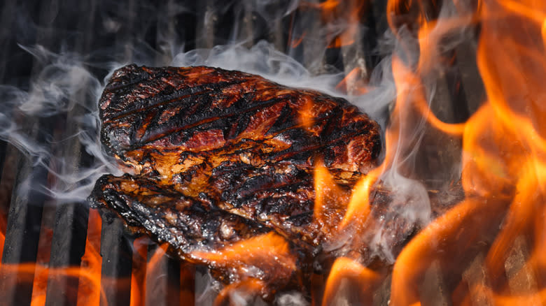 Steaks cooking over fiery grill
