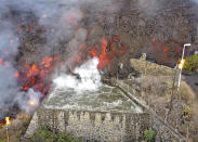 FILE - In this Monday Sept. 20, 2021 file photo, hot lava reaches a balsa normally used for for irrigation after an eruption of a volcano on the island of La Palma in the Canaries, Spain. A long-dormant volcano on a small Spanish island in the Atlantic Ocean erupted on Sunday Sept. 19, 2021, forcing the evacuation of thousands of people. Huge plumes of black-and-white smoke shot out from a volcanic ridge where scientists had been monitoring the accumulation of molten lava below the surface. (Europa Press via AP, File)
