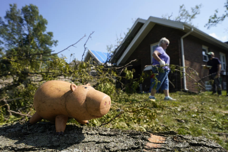 A toy sits on a log as a woman moves branches from a fallen tree to the curb, Friday, Aug. 14, 2020, in Cedar Rapids, Iowa. The storm that struck Monday morning left tens of thousands of Iowans without power as of Friday morning. (AP Photo/Charlie Neibergall)