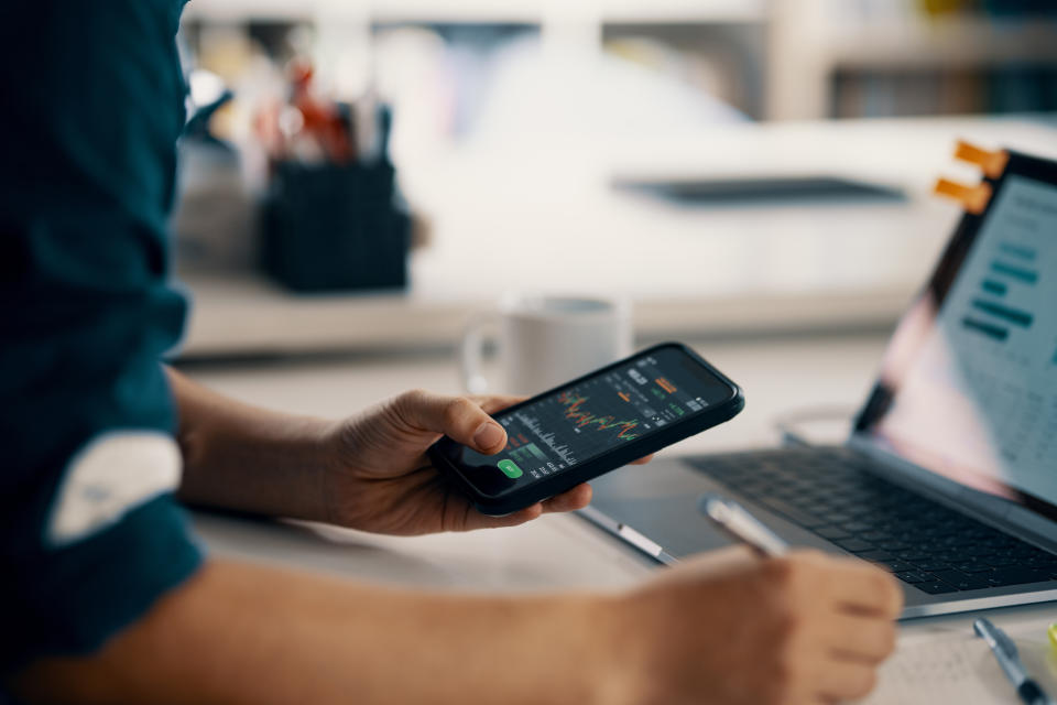 Mid adult man checking financial information on a smart phone while doing his bookkeeping in his home office in Japan.