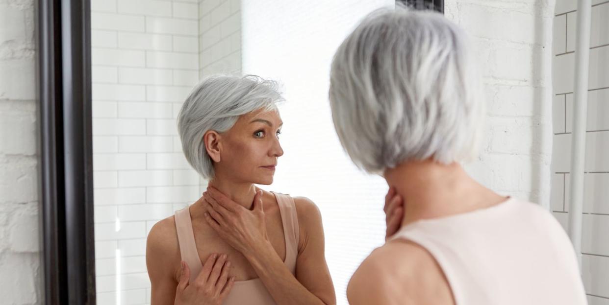 elderly woman at mirror in bathroom