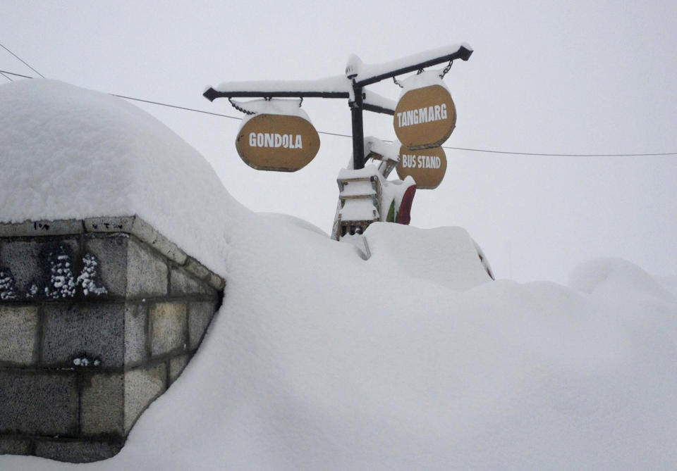 In this photo taken Wednesday, Feb. 27, 2013, signs are seen nearly buried in heavy snow in Gulmarg, Kashmir. Gulmarg, a ski resort nestled in the Himalayan mountains in Indian-held Kashmir is one of the most militarized places on earth. (AP Photo/Kevin Frayer)