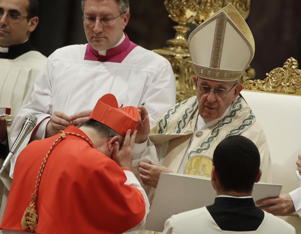 FILE - In this Thursday, June 28, 2018 file photo, Cardinal Giovanni Angelo Becciu receives the red three-cornered biretta hat from Pope Francis during a consistory in St. Peter's Basilica at the Vatican. The Vatican cardinal sacked by Pope Francis amid a corruption investigation is fighting back, suing an Italian newsmagazine and claiming that his ouster has deprived him of the chance of being pope and will undermine the legitimacy of a future papal election. Cardinal Angelo Becciu is seeking 10 million euros in damages, to be given to charity, in a complaint filed in the Sassari, Sardinia tribunal against L’Espresso, the weekly magazine of Italy’s La Repubblica daily. (AP Photo/Alessandra Tarantino, File)