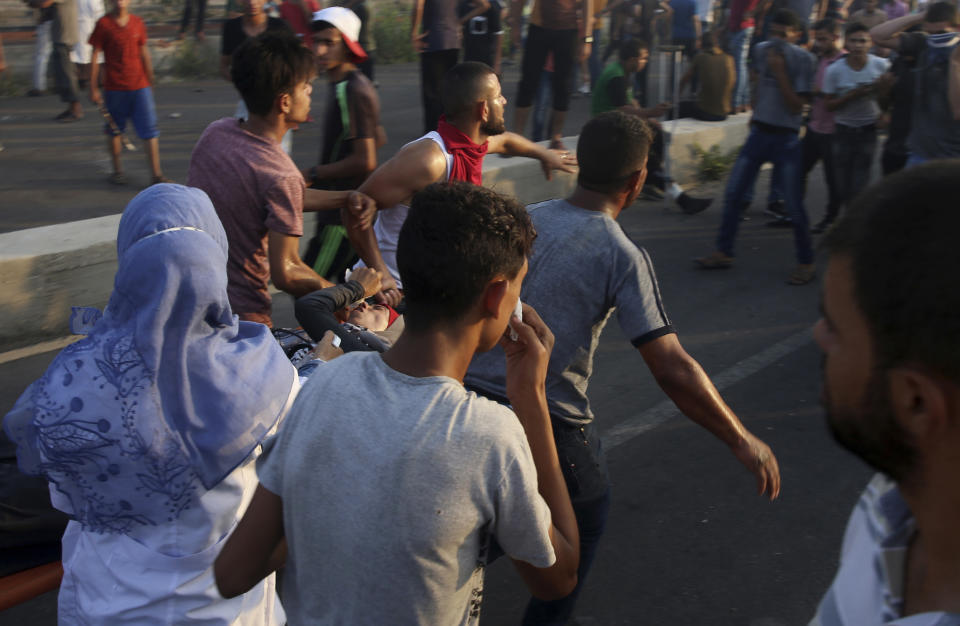 Protesters evacuate a wounded female during a protest at the entrance of Erez border crossing between Gaza and Israel, in the northern Gaza Strip, Tuesday, Sept. 4, 2018. The Health Ministry in Gaza says several Palestinians were wounded by Israeli fire as they protested near the territory's main personnel crossing with Israel. (AP Photo/Adel Hana)