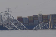 A container rests against wreckage of the Francis Scott Key Bridge on Tuesday, March 26, 2024, as seen from Sparrows Point, Md. The ship rammed into the major bridge in Baltimore early Tuesday, causing it to collapse in a matter of seconds and creating a terrifying scene as several vehicles plunged into the chilly river below. (AP Photo/Matt Rourke)