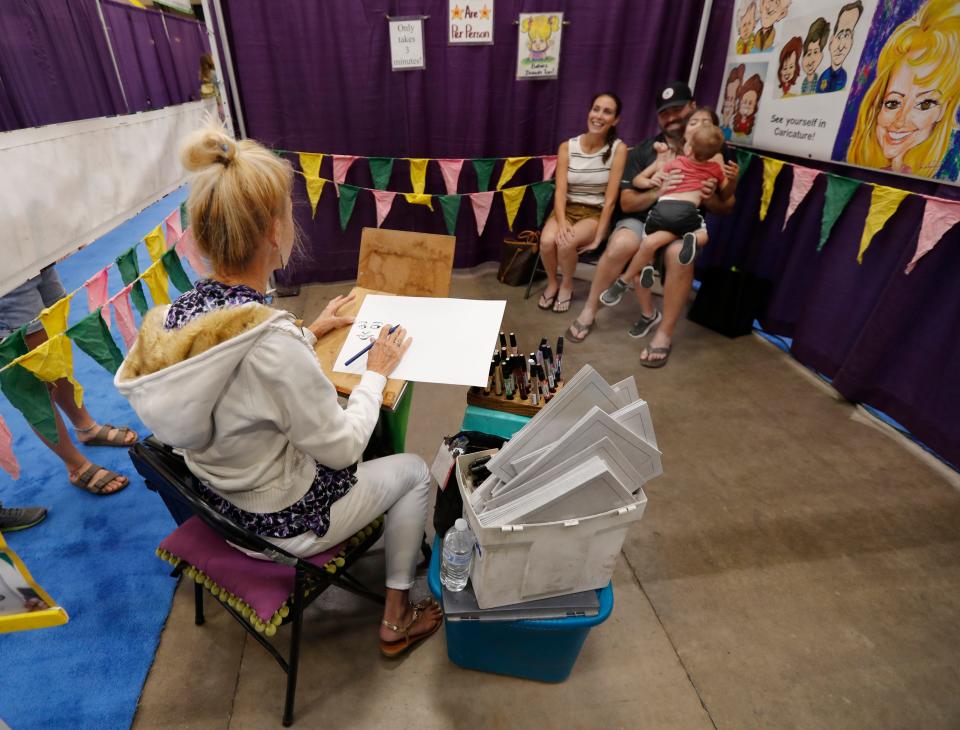 Caricature artist Dorinda Hoke artist draws a picture of Preston and Kim Pehrson and their kids, 7-year-old Austin and 1-year-old Tuff Pehrson Saturday at the Lubbock Arts Festival. The theme for the show was Out of This World: A Celebration of Outer Space, Astronauts, and Space Travel.