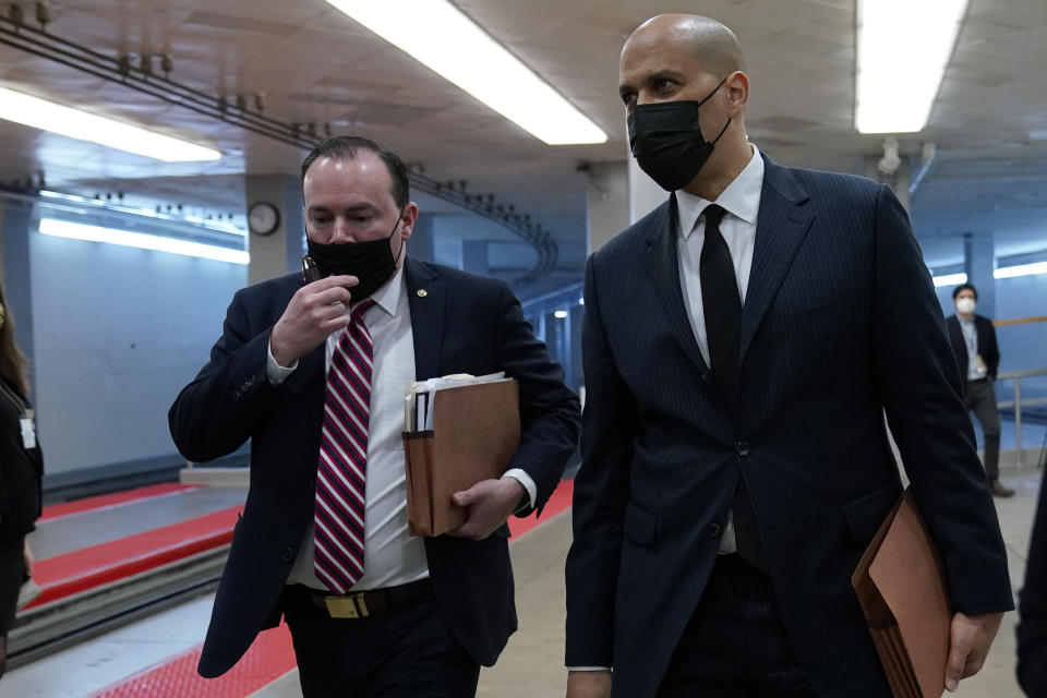 Sen. Mike Lee, R-Utah, left, and Sen. Cory Booker, D-N.J., right, walk on Capitol Hill in Washington, Thursday, Feb. 11, 2021, before the start of the third day of the second impeachment trial of former President Donald Trump. (AP Photo/Susan Walsh)