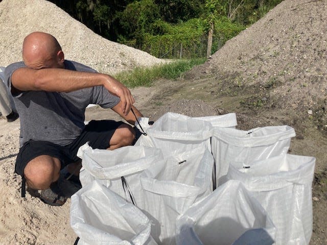 A resident pauses in the Monday morning heat as he loads sandbags at the Mulberry distribution site, one of seven set up by Polk County ahead of Hurricane Ian.