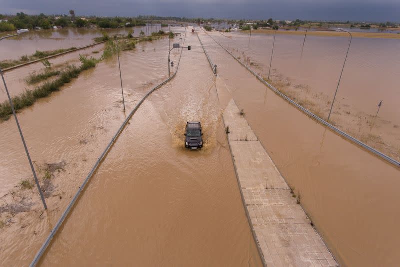 A car is seen on a flooded highway following a storm near the village of Artesiano