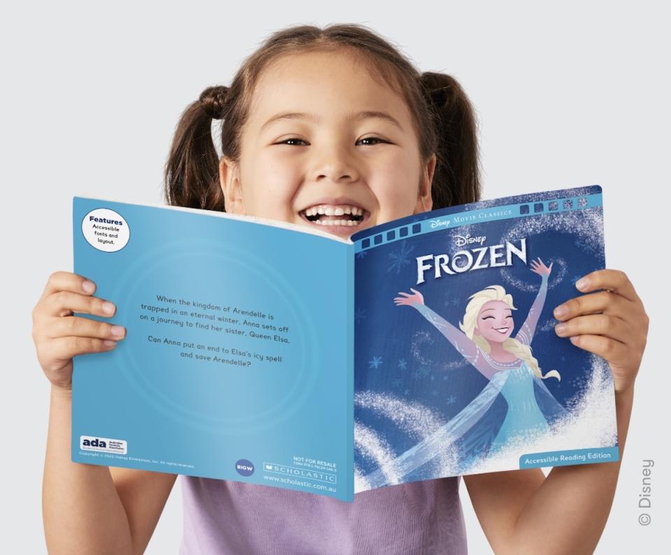 A young girl smiling holding up a copy of Disney's Frozen BIG W