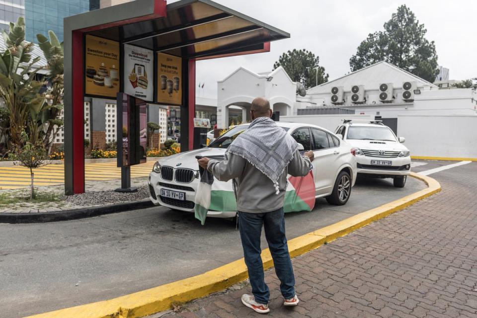A pro-Palestine protester holds a Palestinian flag in a McDonald’s drive-thru. McDonald’s recently bought back all 225 franchise locations in Israel in response to the boycotts (AFP via Getty Images)