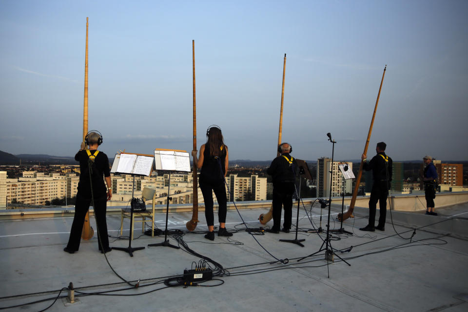 Musicians with alp horns receive applause after performing on the roof of an apartment block for a concert featuring distant harmonies, at a time when cultural events have been disrupted by the coronavirus pandemic, in the Prohlis neighborhood in Dresden, Germany, Saturday, Sept. 12, 2020. About 33 musicians of the Dresden Sinfoniker perform a concert named the 'Himmel ueber Prohils', The Sky above Prohlis, on the roof-tops of communist-era apartment blocs in the Dresden neighborhood Prohlis. (AP Photo/Markus Schreiber)