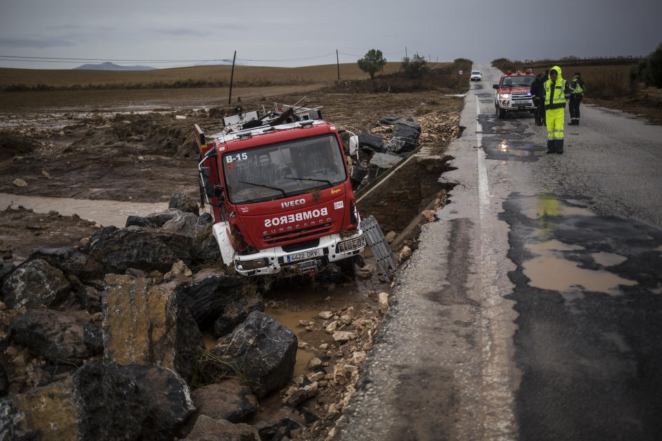 A firefighting truck can be seen off the road, where heavy rain and floods have caused severe damage and the death of a firefighter according to Spanish authorities, near the village of Campillos, Spain, Sunday, Oct. 21 2018. Emergency services for the southern region of Andalusia say that the firefighter went missing when his truck overturned on a flooded road during heavy rains that fell through the night, and his body was found after a search Sunday morning. (AP Photo/Javier Fergo)