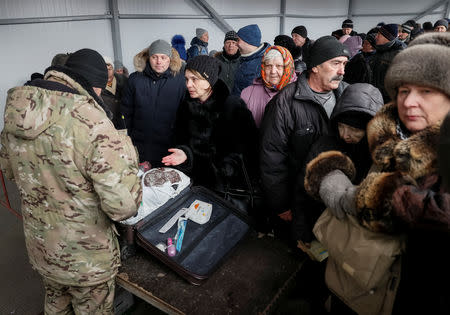 People line up as border guards check their luggage before they go through passport control, after crossing the contact line between pro-Russian rebels and Ukrainian troops in Mayorsk, Ukraine, February 25, 2019. More than a million people cross the 500 km contact line every year, many of them are pensioners who spend hours queuing, in cold, heat, rain or snow, as they rely on state benefits that can only be obtained on the government-controlled side. REUTERS/Gleb Garanich