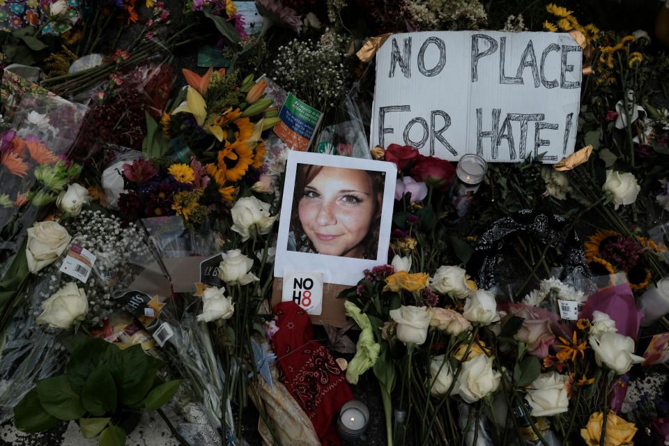 A photograph of Charlottesville victim Heather Heyer is seen among flowers, candles and a sign that reads: No place for hate.