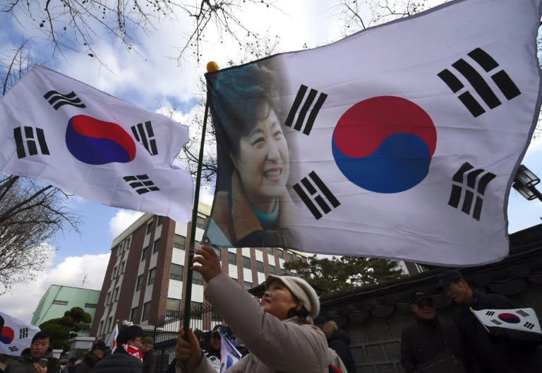 A pro-government activist waves a national flag showing a portrait of South Korea's President Park Geun-Hye during a rally opposing impeachment of the President near the Constitutional Court in Seoul on March 9, 2017