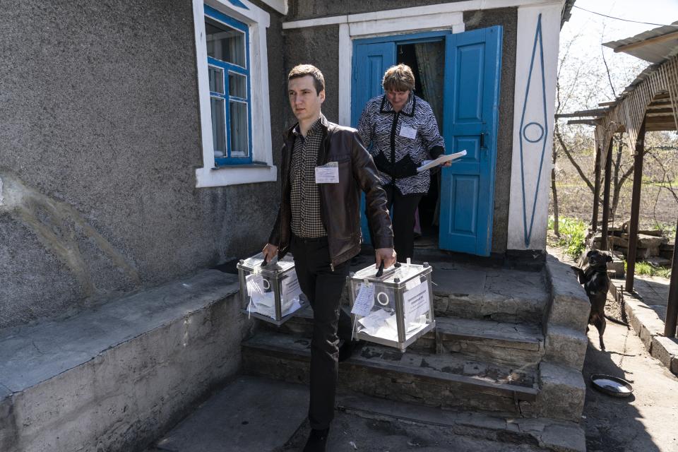 An election commission member leaves a private house after helping an elderly woman vote during the second round of presidential elections in Novomykhailivka, Donetsk region, eastern Ukraine, Sunday, April 21, 2019. Ukrainians cast ballots Sunday in a presidential runoff which had the incumbent struggling to fend off a strong challenge by a comedian who denounces corruption and plays the role of president in a TV sitcom. (AP Photo/Evgeniy Maloletka)