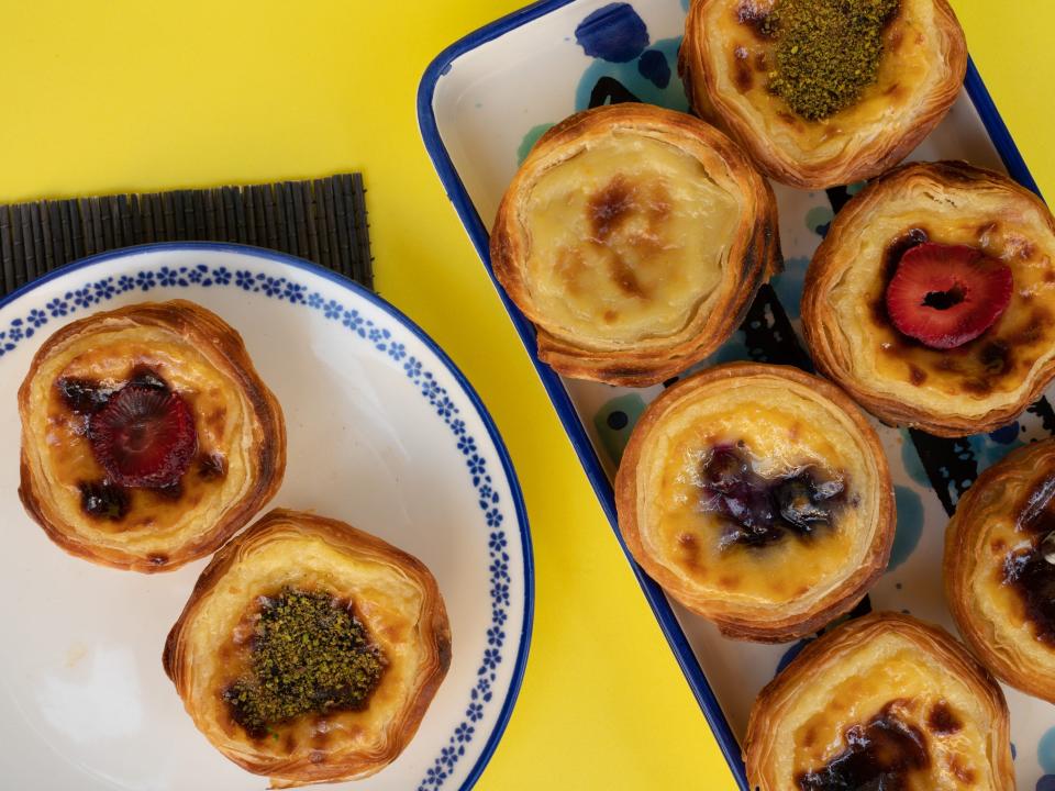 Pastel De Nata, traditional Portuguese Custard Tarts. Different types Belem pies in plates on yellow background.