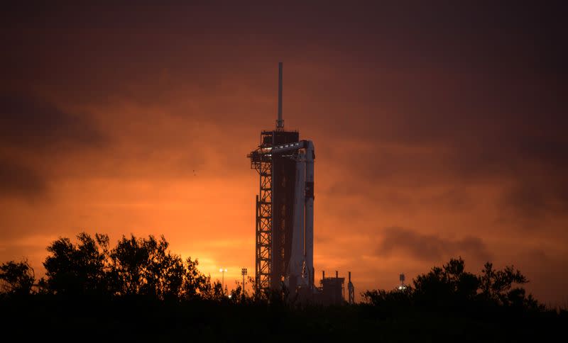 The sun sets behind a SpaceX Falcon 9 rocket with the company's Crew Dragon spacecraft onboard