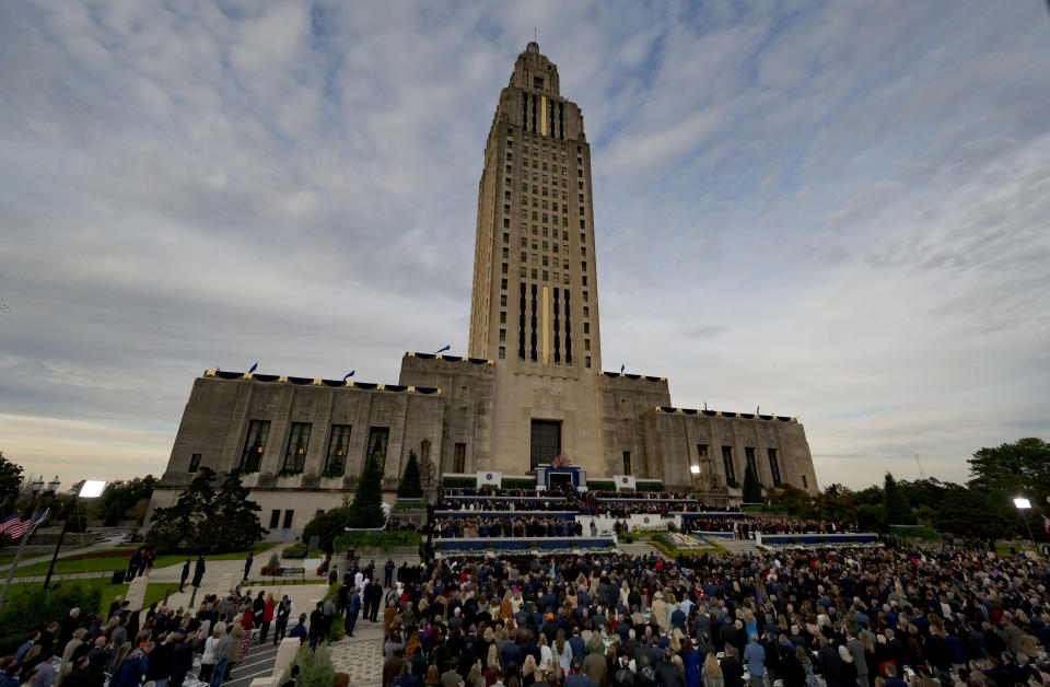 At twilight, people listen to Louisiana Republican Gov. Jeff Landry speak during his inauguration ceremony at the State Capitol building in Baton Rouge, La., Sunday, Jan. 7, 2024. The ceremony was moved because of forecasted rain on Monday, Jan. 8, the actual date Landry officially becomes governor. (AP Photo/Matthew Hinton)