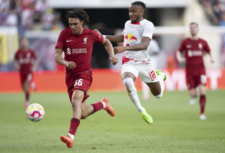 Trent Alexander-Arnold, izquierda, del Liverpool, y Christopher Nkunku, del Leipzig,  disputan el balón en un amistoso en la Arena Red Bull de Leipzig, Alemania, el jueves 21 de julio de 2022. (Hendrik Schmidt/dpa vía AP)