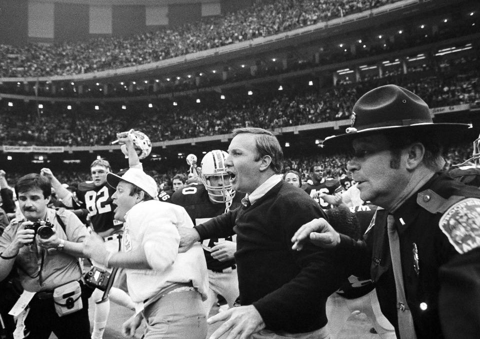 FILE - In this Jan. 3, 1984, file photo, Auburn head coach Pat Dye, center, rushes onto the field after his team beat Michigan 9-7 in the Sugar Bowl at the Superdome in New Orleans. Former Auburn coach Pat Dye, who took over a downtrodden football program in 1981 and turned it into a Southeastern Conference power, has died. He was 80. Lee County Coroner Bill Harris said Dye passed away Monday, June 1, 2020, at the Compassus Bethany House in Auburn, Ala.(AP Photo, File)