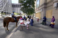 CORRECTS YEAR TO 2020 NOT 2019 A Chicago mounted police officer and his horse interact with shoppers as he patrols the city's Magnificent Mile on Tuesday, Aug. 11, 2020. Store owners in and around Chicago's Michigan Avenue are asking themselves if of the economics and reputation of one America’s most prestigious shopping districts can rebound from the damage caused by looting this week. Businesses had been slowly reopening after pandemic-related shutdowns. (AP Photo/Charles Rex Arbogast)