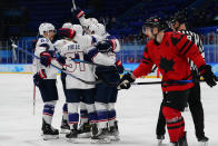 United States players celebrate after a goal by Kenny Agostino as Canada's Maxim Noreau (56) skates by during a preliminary round men's hockey game at the 2022 Winter Olympics, Saturday, Feb. 12, 2022, in Beijing. (AP Photo/Matt Slocum)
