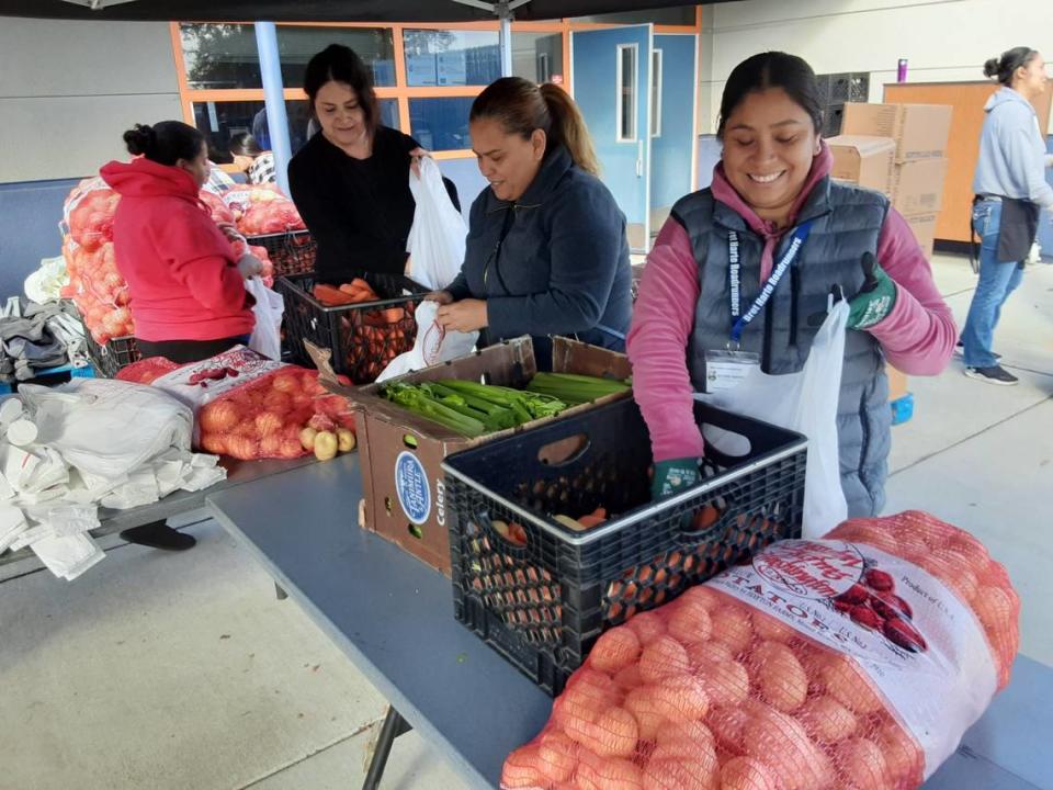 Parent volunteers fill bags with potatoes, carrots and celery at Bret Harte Elementary School in south Modesto on Thursday, Nov. 10, 2022.