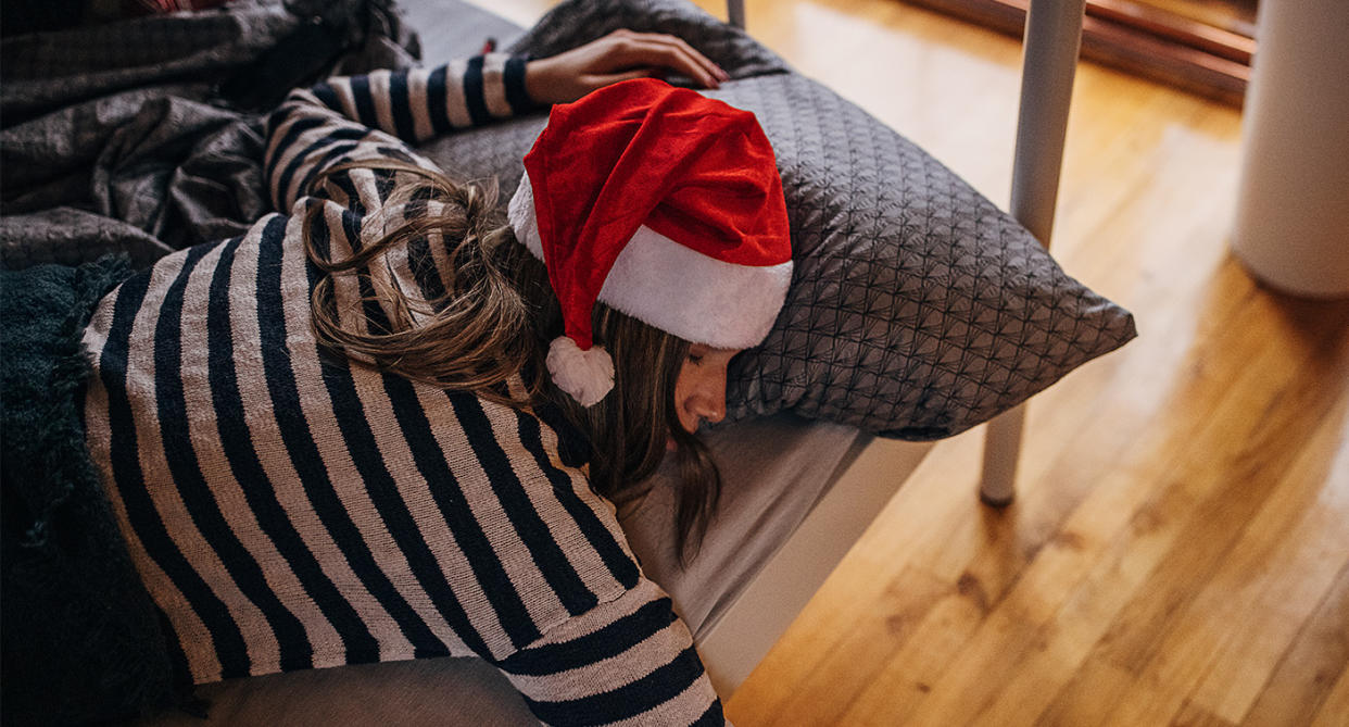 Someone having a hangover with Christmas hat on in bed. (Getty Images)