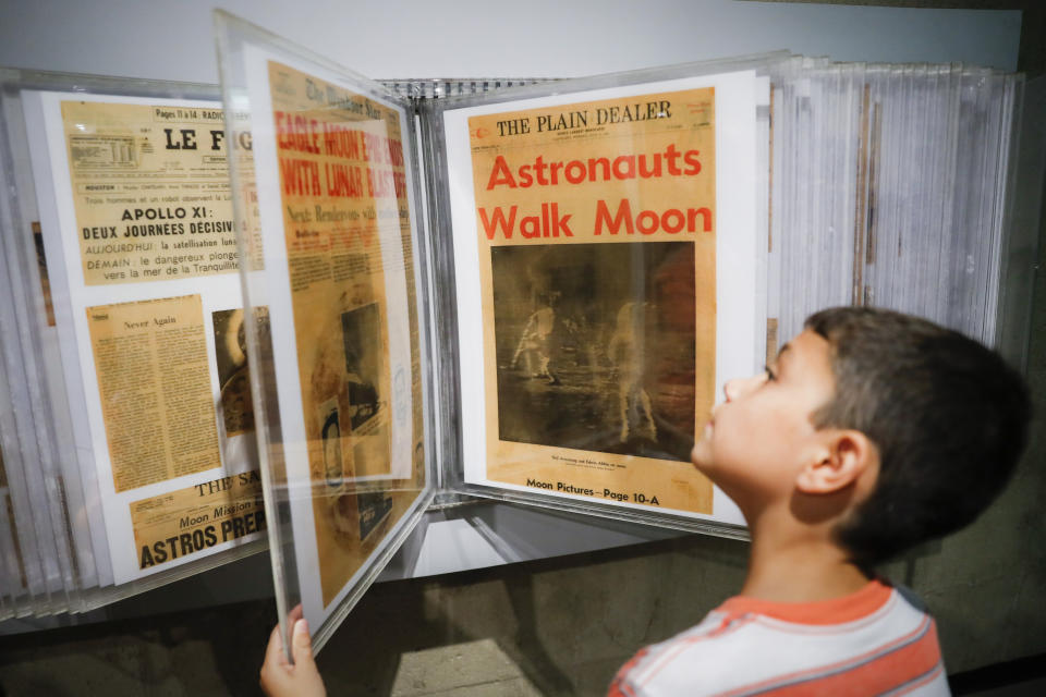 Ethan Reynolds browses a display of archival newspaper front pages announcing the first moon landing at the Armstrong Air and Space Museum as special events are underway for visitors commemorating the milestone's 50th anniversary, Saturday, July 20, 2019, in Wapakoneta, Ohio. (AP Photo/John Minchillo)