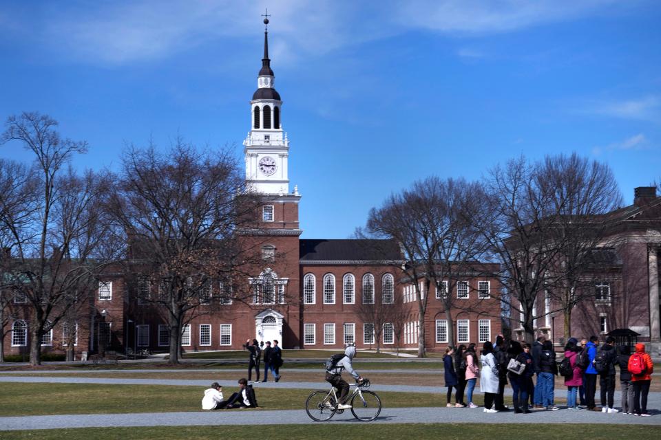 A bicyclist passes a college tour group outside the Baker Library at Dartmouth College on April 7, 2023, in Hanover, N.H.