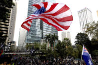 A participant waves a U.S. flag as a colonial flag is seen on right during a rally demanding electoral democracy and call for boycott of the Chinese Communist Party and all businesses seen to support it in Hong Kong, Sunday, Jan. 19, 2020. Hong Kong has been wracked by often violent anti-government protests since June, although they have diminished considerably in scale following a landslide win by opposition candidates in races for district councilors late last year. (AP Photo/Ng Han Guan)